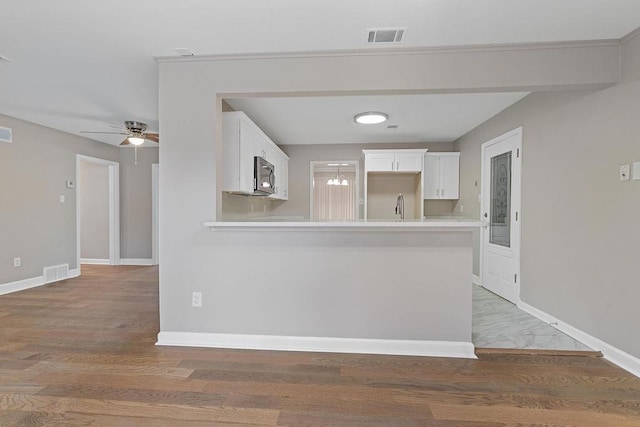 kitchen featuring wood-type flooring, sink, white cabinets, and kitchen peninsula