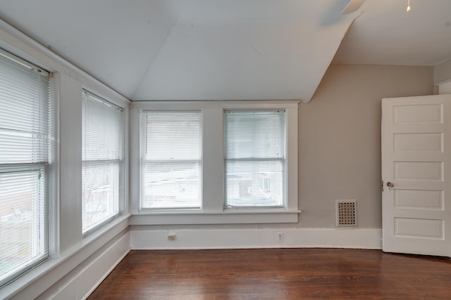 unfurnished room with lofted ceiling, dark wood-type flooring, and a healthy amount of sunlight