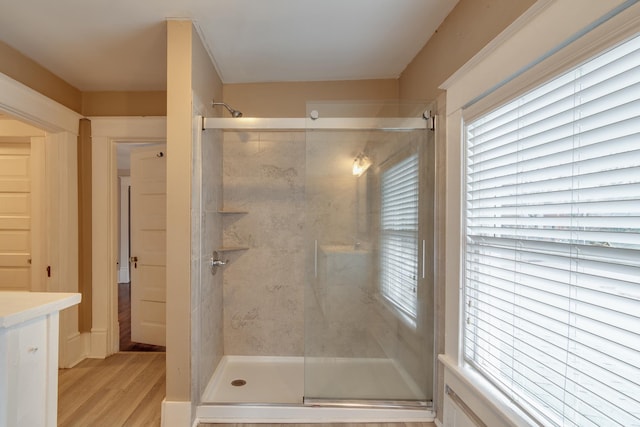 bathroom with a wealth of natural light, hardwood / wood-style floors, and an enclosed shower