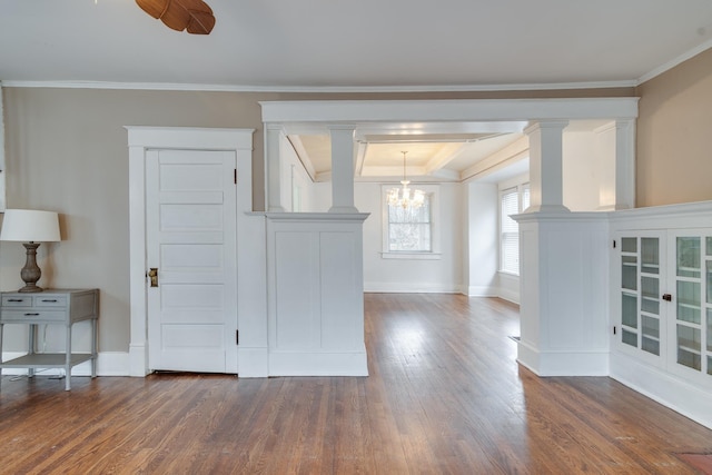 interior space featuring ornate columns, ornamental molding, dark wood-type flooring, and an inviting chandelier