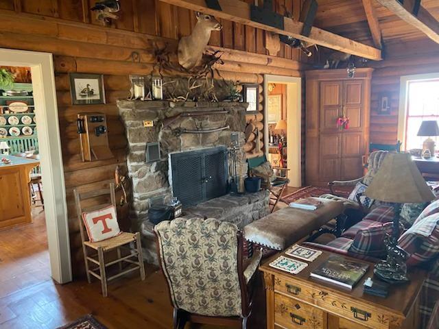 living room featuring wood ceiling, wood-type flooring, a stone fireplace, and lofted ceiling with beams