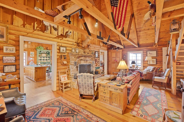 living room with wood ceiling, high vaulted ceiling, a stone fireplace, and light hardwood / wood-style floors