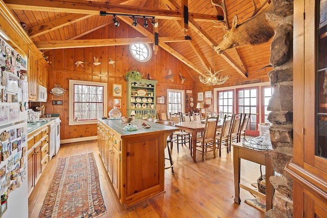 kitchen with wood ceiling, light wood-type flooring, wood walls, and a kitchen island