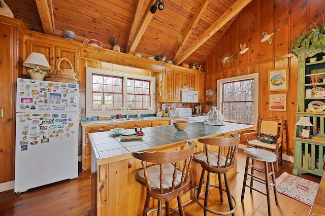 kitchen with sink, white appliances, a wealth of natural light, tile countertops, and wood walls