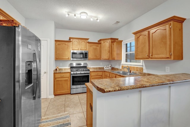 kitchen featuring light tile patterned flooring, sink, kitchen peninsula, stainless steel appliances, and a textured ceiling