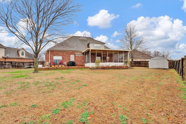 back of property featuring a storage shed, a lawn, and a sunroom