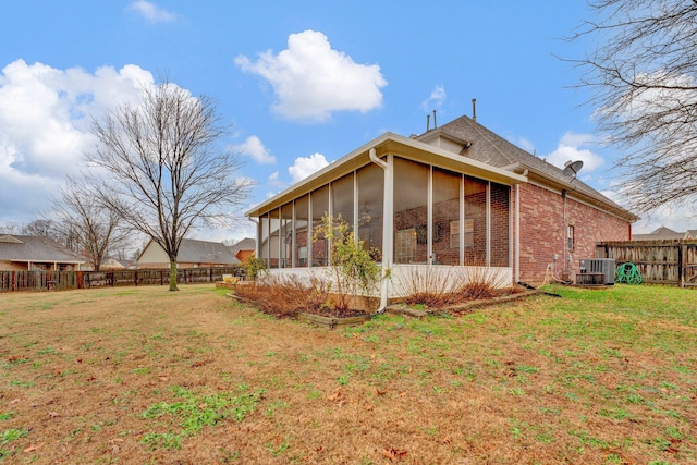 rear view of house featuring a sunroom, cooling unit, and a lawn