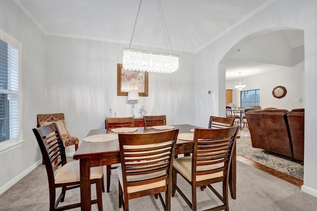 dining room with crown molding, light colored carpet, and a notable chandelier