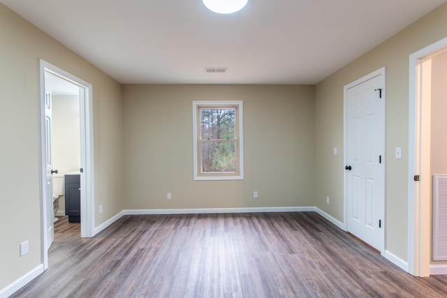 unfurnished bedroom with connected bathroom and hardwood / wood-style floors