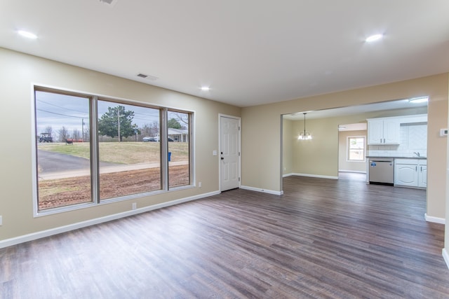 unfurnished living room featuring a notable chandelier and dark hardwood / wood-style flooring