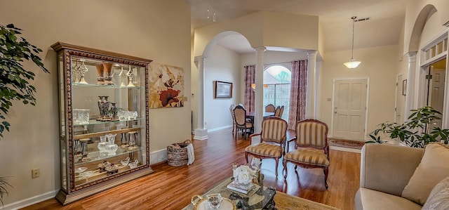 living room featuring hardwood / wood-style flooring, a towering ceiling, and ornate columns