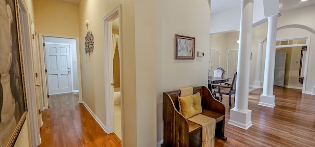 corridor featuring ornate columns, a high ceiling, and hardwood / wood-style flooring