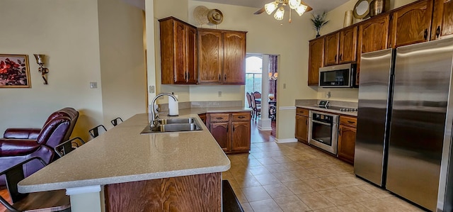 kitchen featuring sink, a kitchen breakfast bar, stainless steel appliances, light tile patterned flooring, and kitchen peninsula