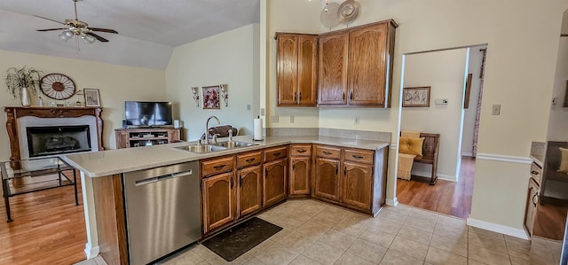 kitchen featuring lofted ceiling, sink, ceiling fan, stainless steel dishwasher, and kitchen peninsula