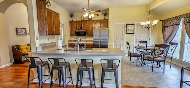 kitchen featuring appliances with stainless steel finishes, sink, a kitchen bar, hanging light fixtures, and kitchen peninsula