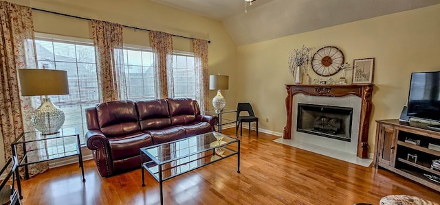 living room with lofted ceiling, a fireplace, and light wood-type flooring