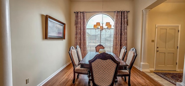 dining space featuring an inviting chandelier, wood-type flooring, and ornate columns