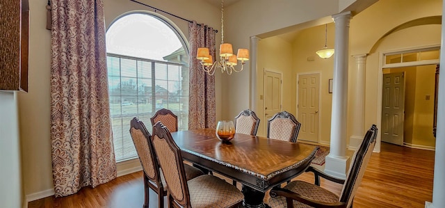 dining room featuring dark wood-type flooring, decorative columns, and a notable chandelier