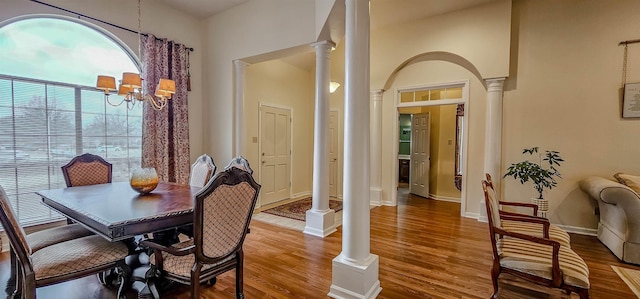 dining space featuring a chandelier, hardwood / wood-style floors, a high ceiling, and ornate columns