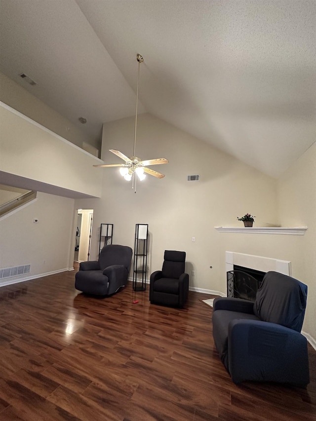 living room featuring dark hardwood / wood-style flooring, a textured ceiling, high vaulted ceiling, and ceiling fan