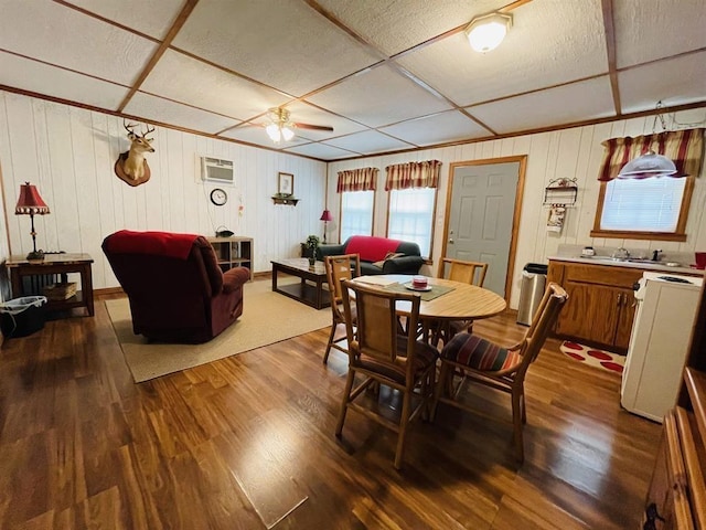 dining area featuring ceiling fan, wood-type flooring, sink, and a wall unit AC