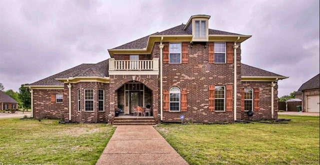 view of front facade with a balcony and a front lawn