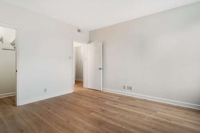 unfurnished bedroom featuring a walk in closet, a closet, and light hardwood / wood-style flooring