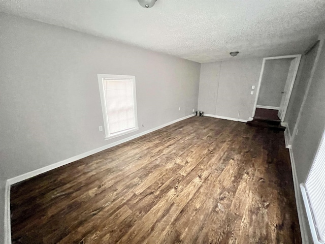 spare room featuring dark wood-type flooring and a textured ceiling