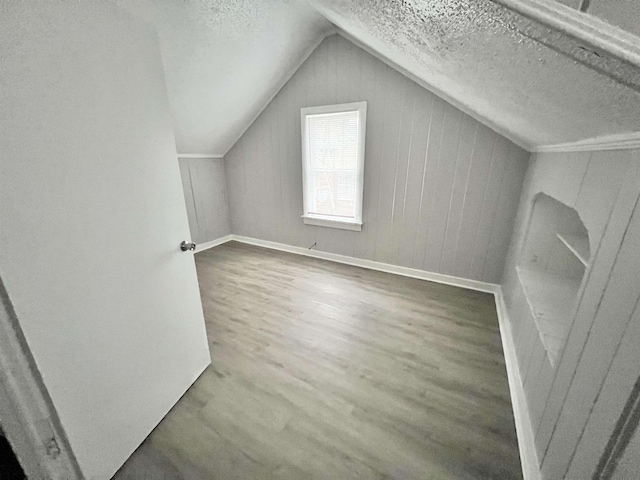 bonus room with hardwood / wood-style flooring, vaulted ceiling, and a textured ceiling