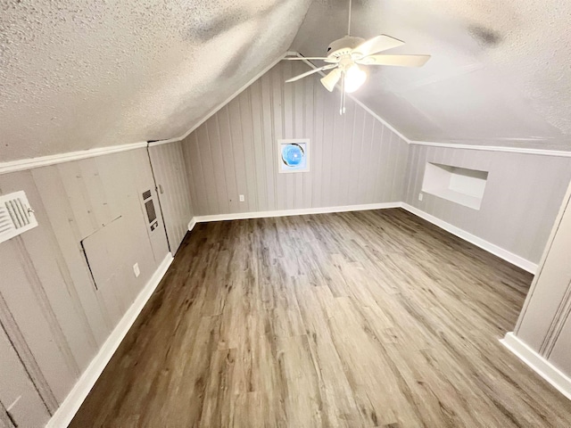 additional living space featuring lofted ceiling, hardwood / wood-style floors, a textured ceiling, and ceiling fan