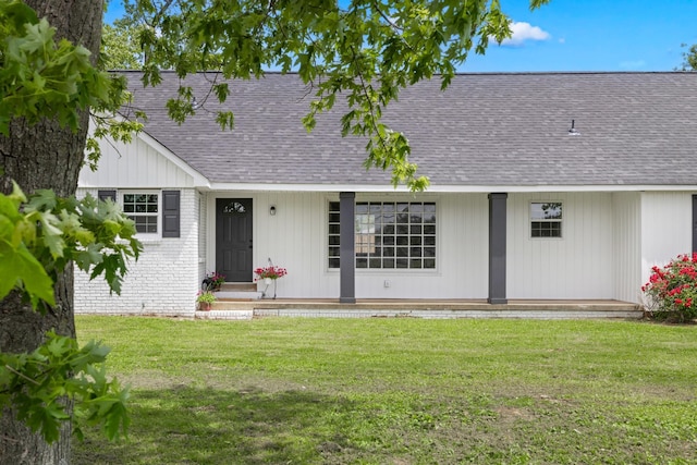 view of front facade featuring a front yard, brick siding, and roof with shingles