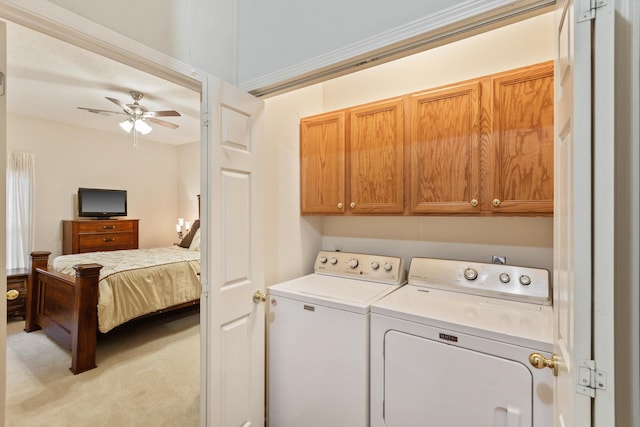 clothes washing area with washing machine and clothes dryer, cabinets, light carpet, ornamental molding, and ceiling fan