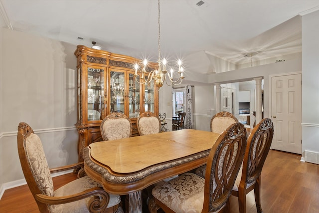 dining area featuring ornate columns, lofted ceiling, dark hardwood / wood-style floors, and a notable chandelier