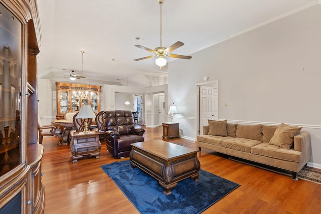 living room featuring hardwood / wood-style flooring, crown molding, lofted ceiling, and ceiling fan with notable chandelier