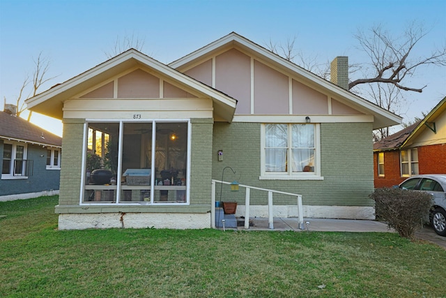 back of house with a lawn and a sunroom