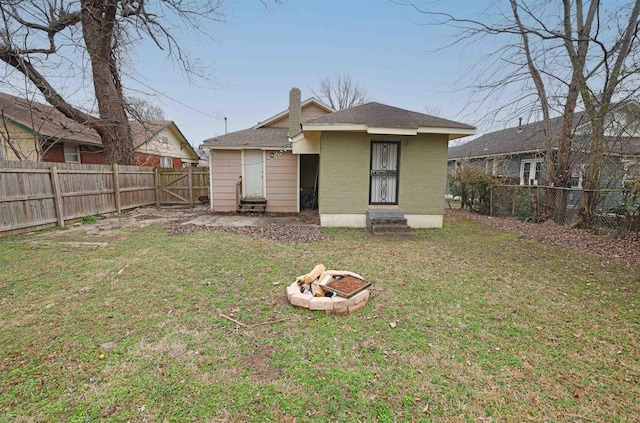 rear view of house with a yard and a fire pit