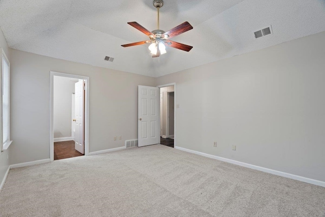 unfurnished bedroom with connected bathroom, lofted ceiling, carpet, ceiling fan, and a textured ceiling