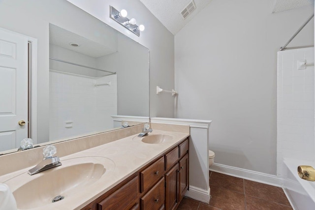 full bathroom with vaulted ceiling, vanity, toilet, tile patterned floors, and a textured ceiling