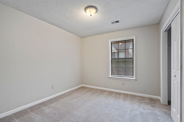 unfurnished bedroom with a closet, light carpet, and a textured ceiling