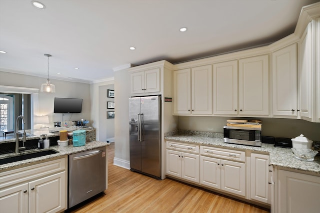 kitchen featuring sink, light hardwood / wood-style flooring, hanging light fixtures, stainless steel appliances, and light stone counters