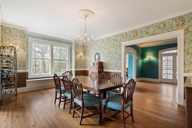 dining area with wood-type flooring, a healthy amount of sunlight, and a notable chandelier