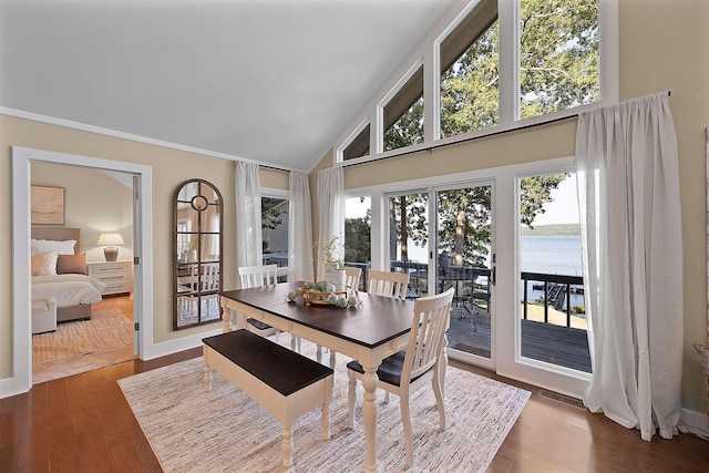 dining space featuring dark wood-type flooring, high vaulted ceiling, and a water view