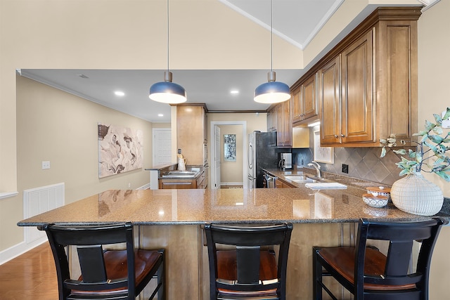 kitchen featuring light stone counters, decorative light fixtures, a breakfast bar area, and kitchen peninsula