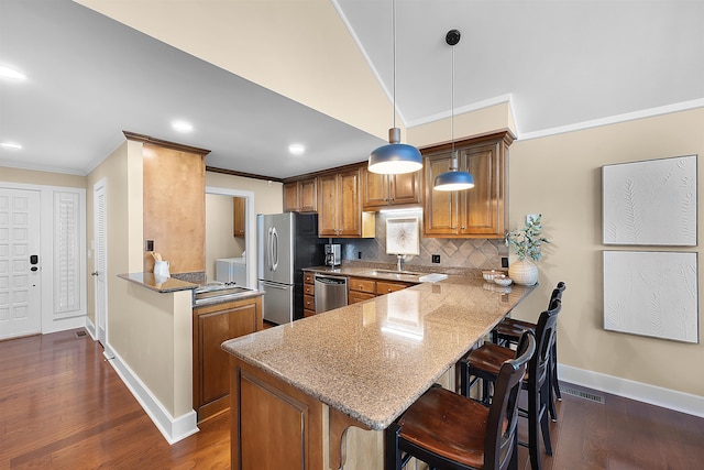 kitchen featuring pendant lighting, stainless steel appliances, kitchen peninsula, and a breakfast bar area