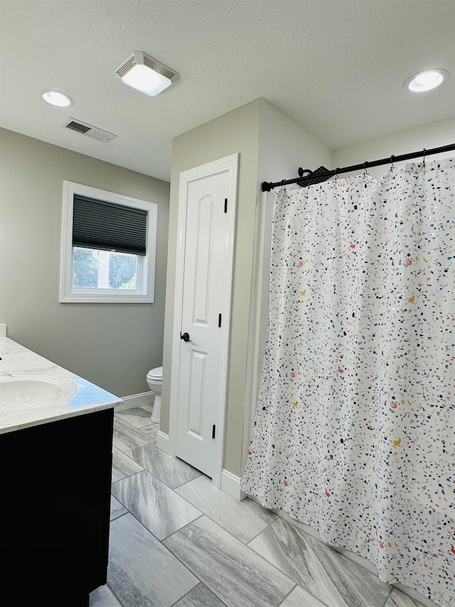 bathroom featuring vanity, walk in shower, a textured ceiling, and toilet