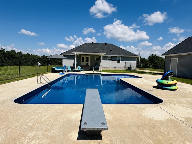 view of swimming pool featuring a diving board and a patio area