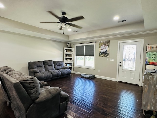 living room with ceiling fan, a tray ceiling, and dark hardwood / wood-style flooring