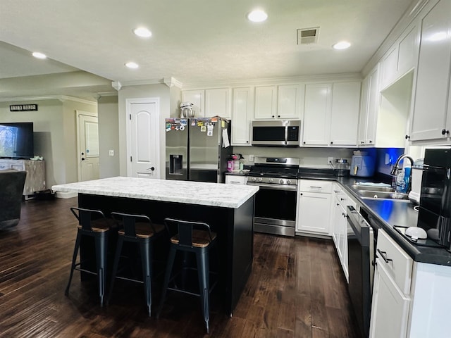 kitchen with stainless steel appliances, a kitchen bar, a kitchen island, and white cabinets