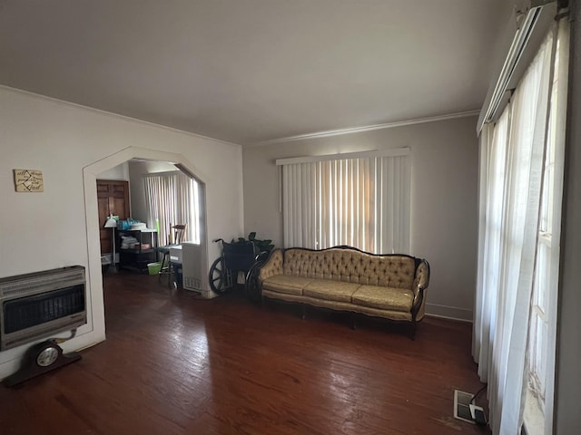 living room with heating unit, dark wood-type flooring, and ornamental molding