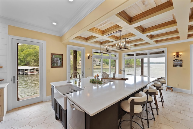 kitchen featuring decorative light fixtures, beamed ceiling, coffered ceiling, a kitchen island with sink, and a water view